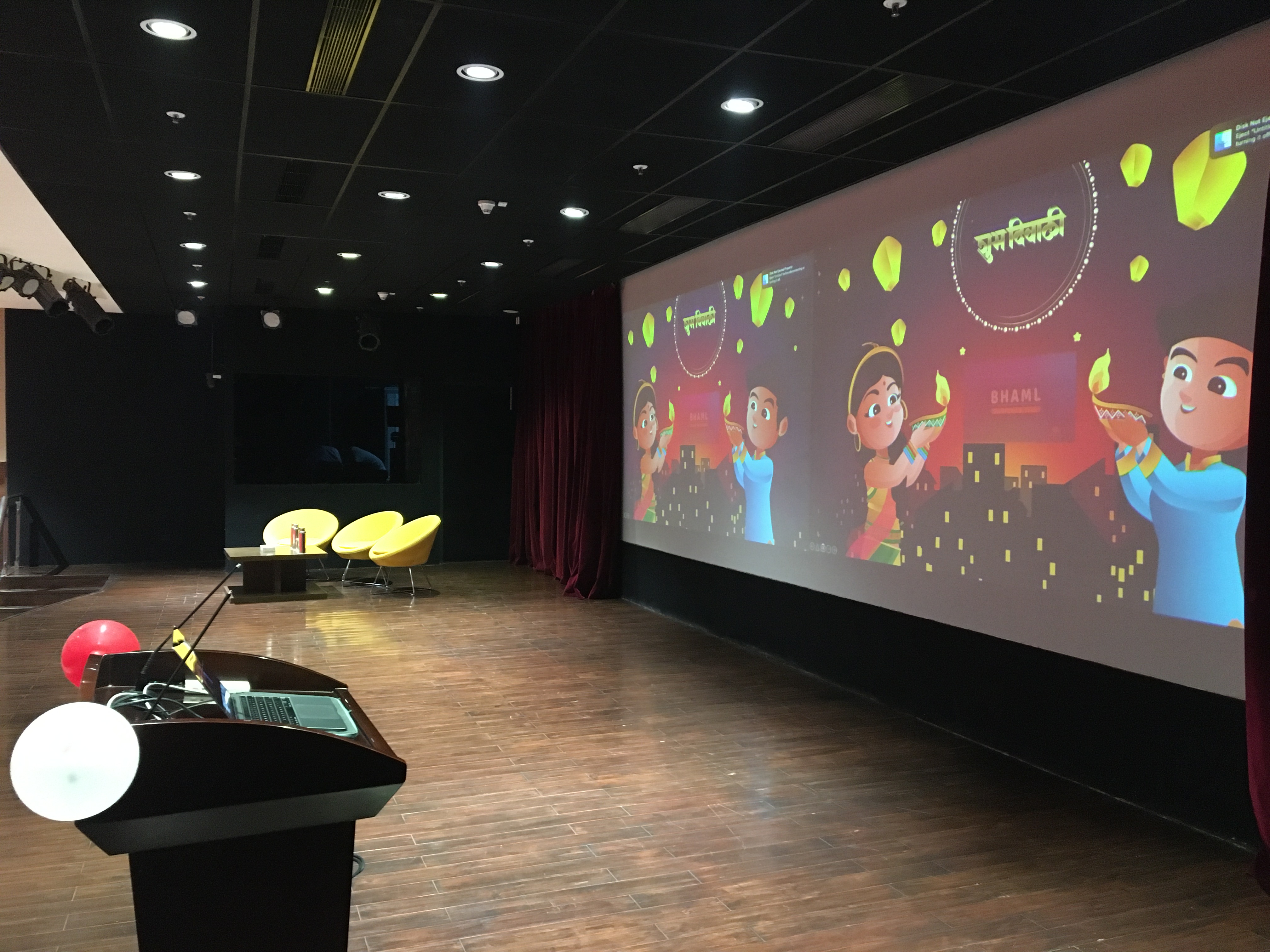 Large presentation hall with BHAML branding and animated content