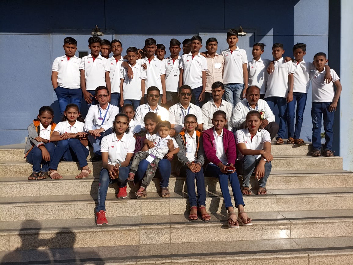 Large group of students in white polo shirts on institutional steps